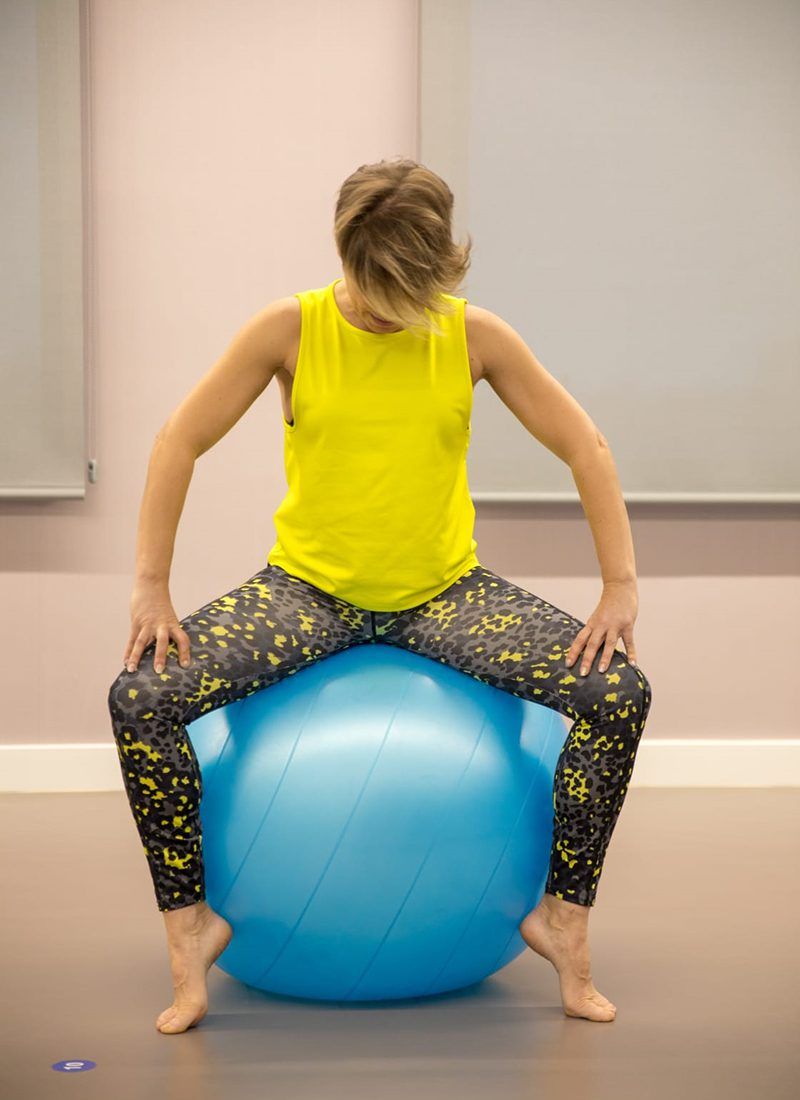 Chica haciendo un ejercicio de pilates sentada en una pelota de Fitball