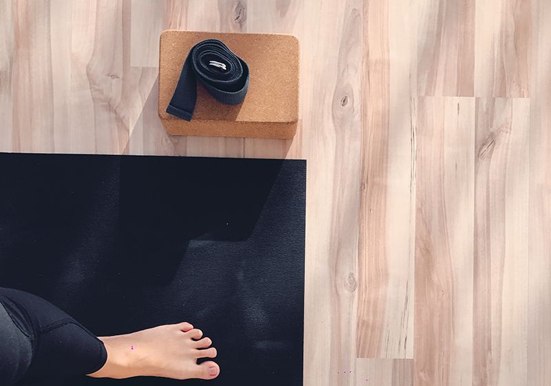 Imagen vertical donde se ve un pie descalzo sobre una esterilla y una cinta para una clase de yoga